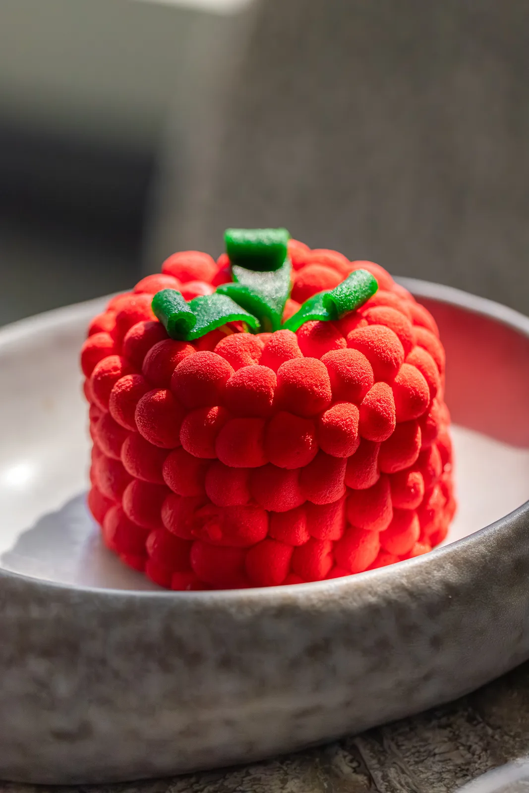 Sculpted raspberry-shaped mousse dessert in a ceramic bowl