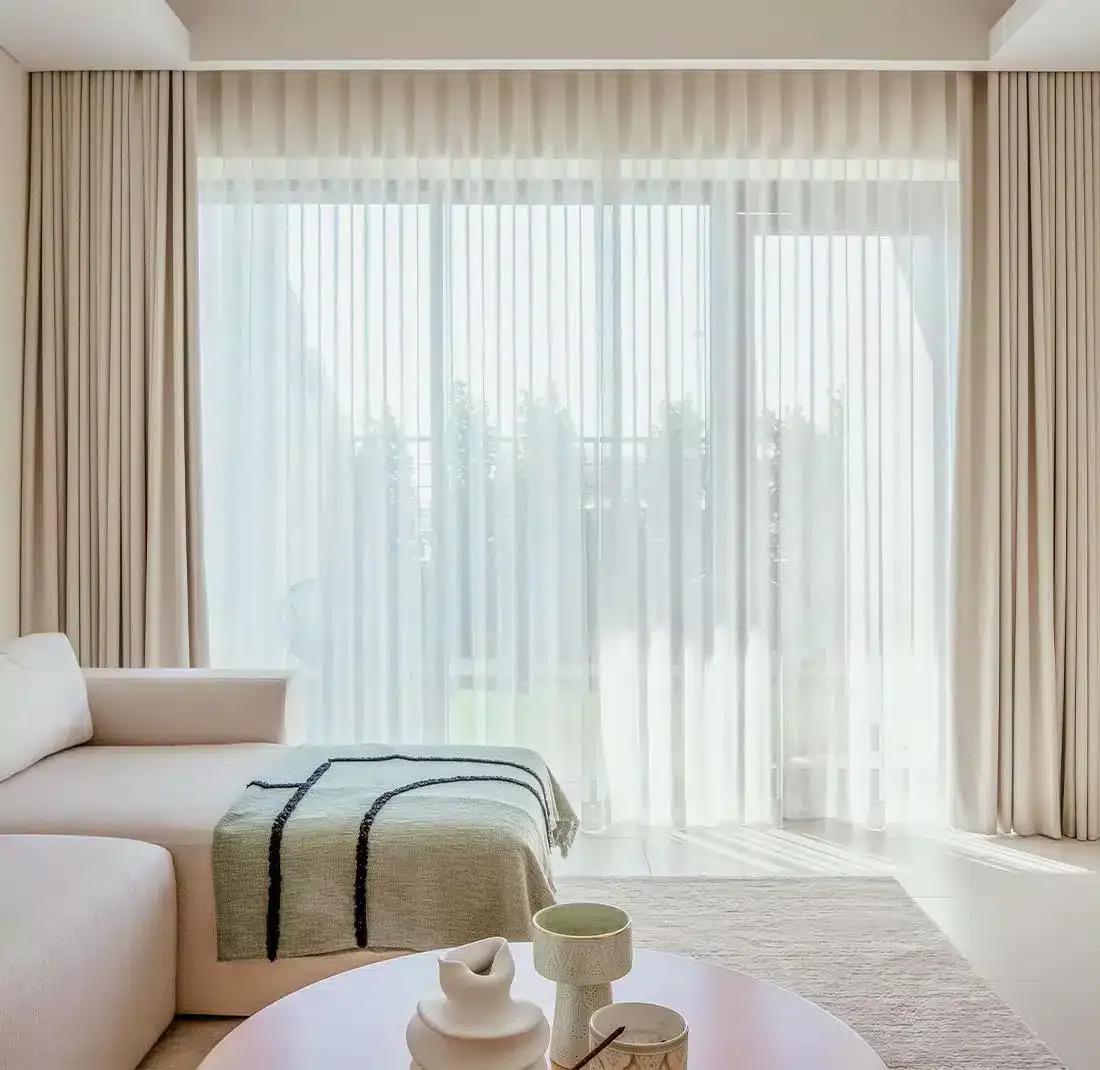 Bedroom with full-width sheer curtains diffusing soft daylight