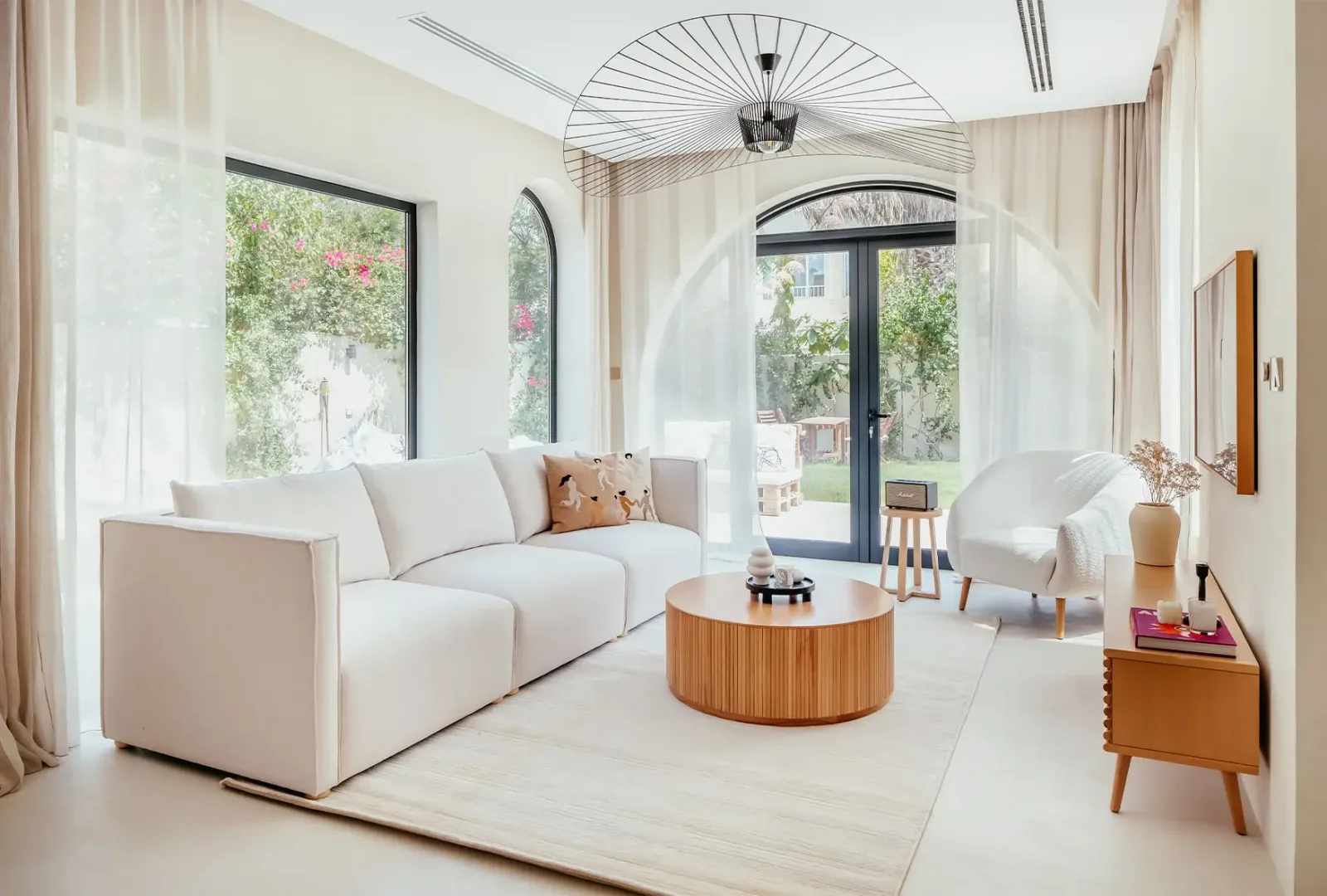 A bright Dubai living room dressed with floor-to-ceiling sheer curtains and linen drapes
