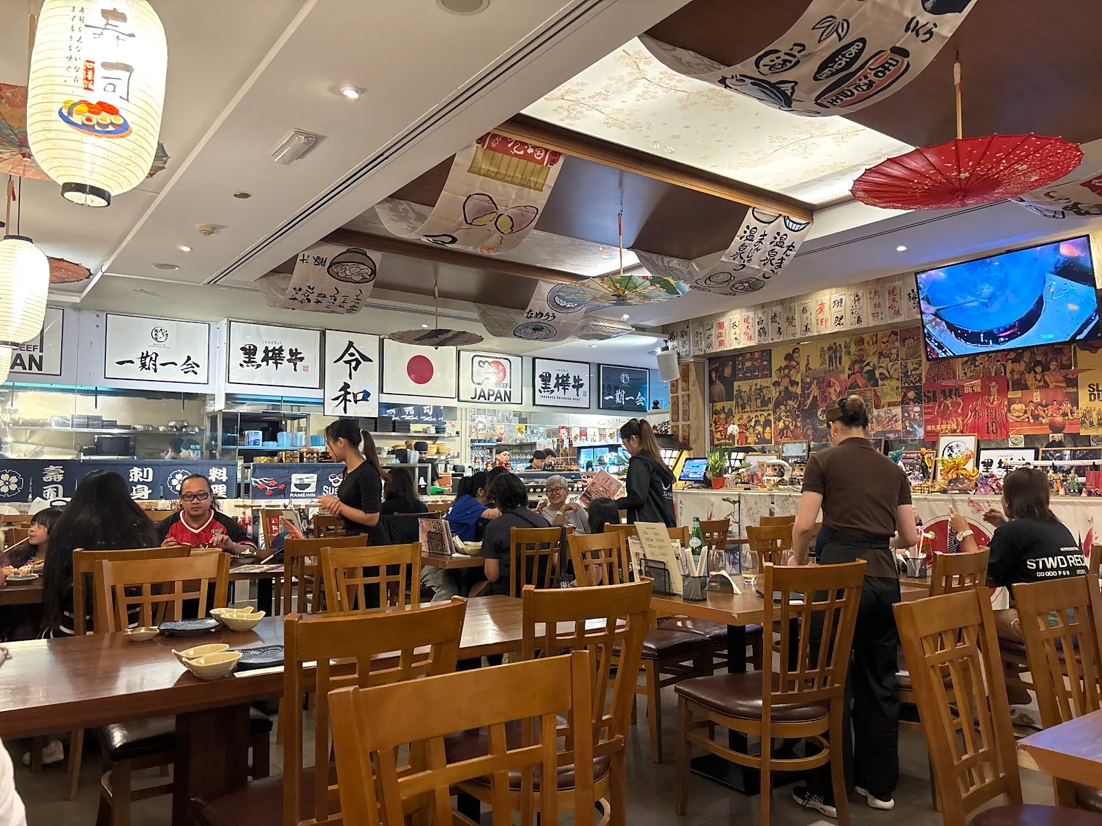 Mogi-ya dining room with paper lanterns, hanging banners, parasols and an open kitchen