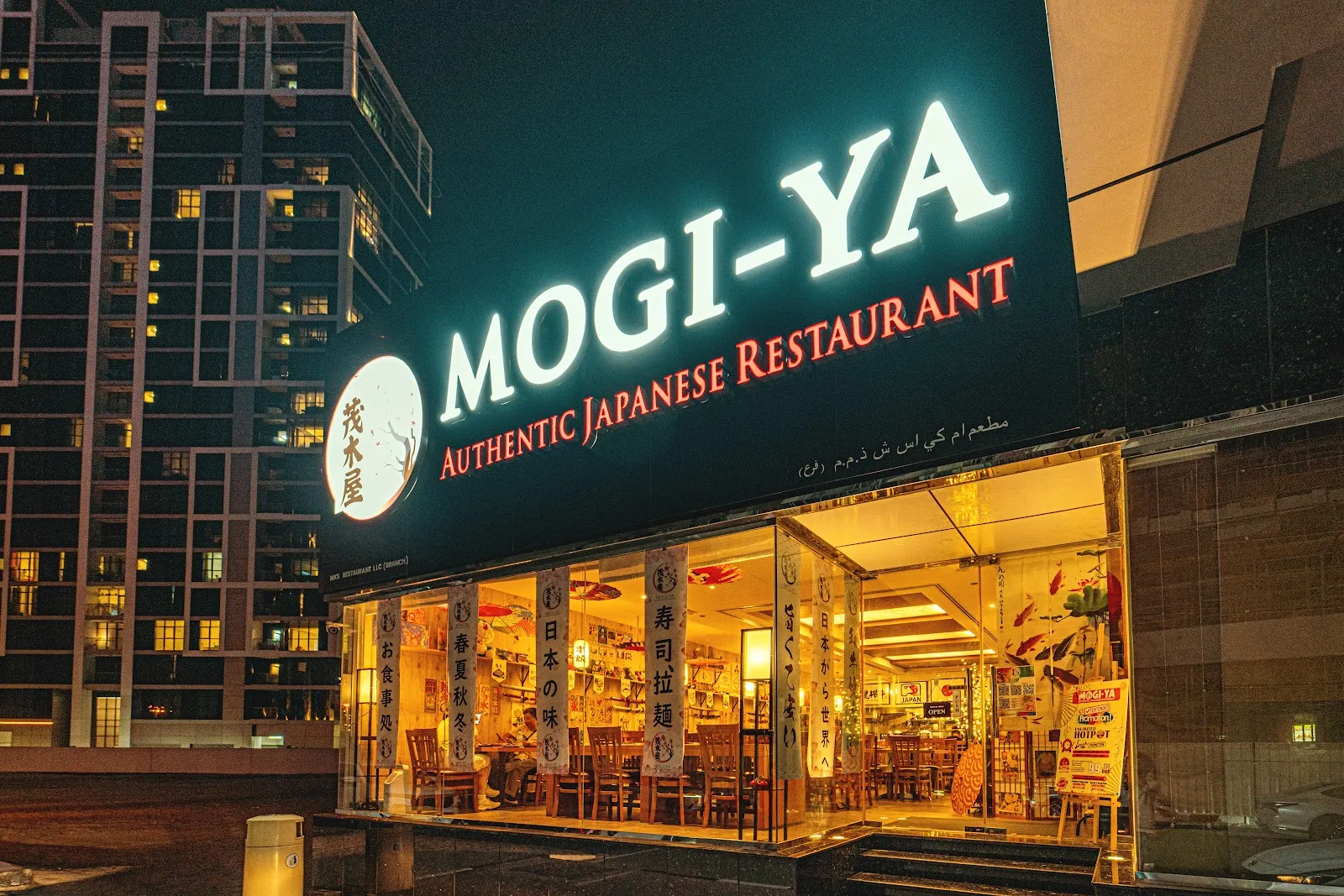 Mogi-ya storefront at night with the illuminated MOGI-YA Authentic Japanese Restaurant sign