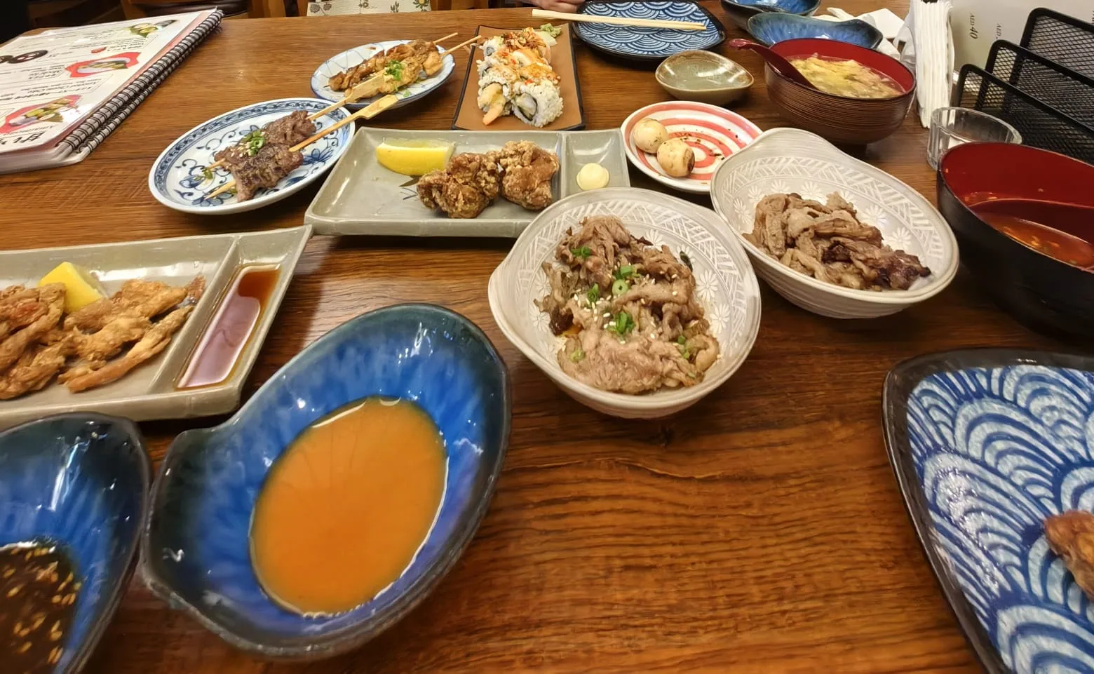 Shared table with sushi, grilled beef bowls and karaage