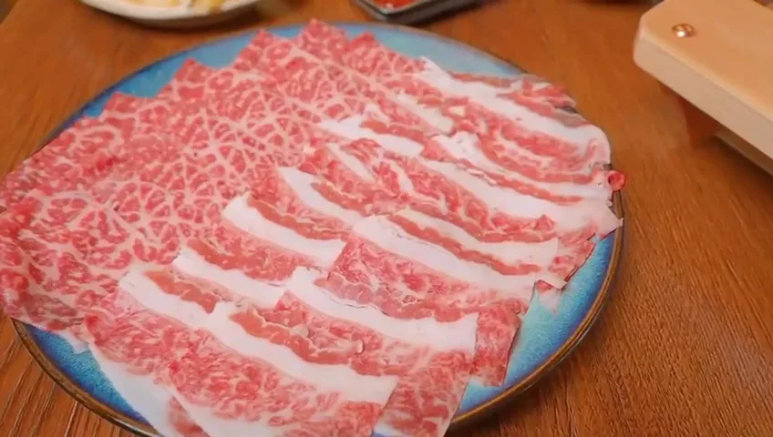 Plate of thinly sliced marbled beef for grilling