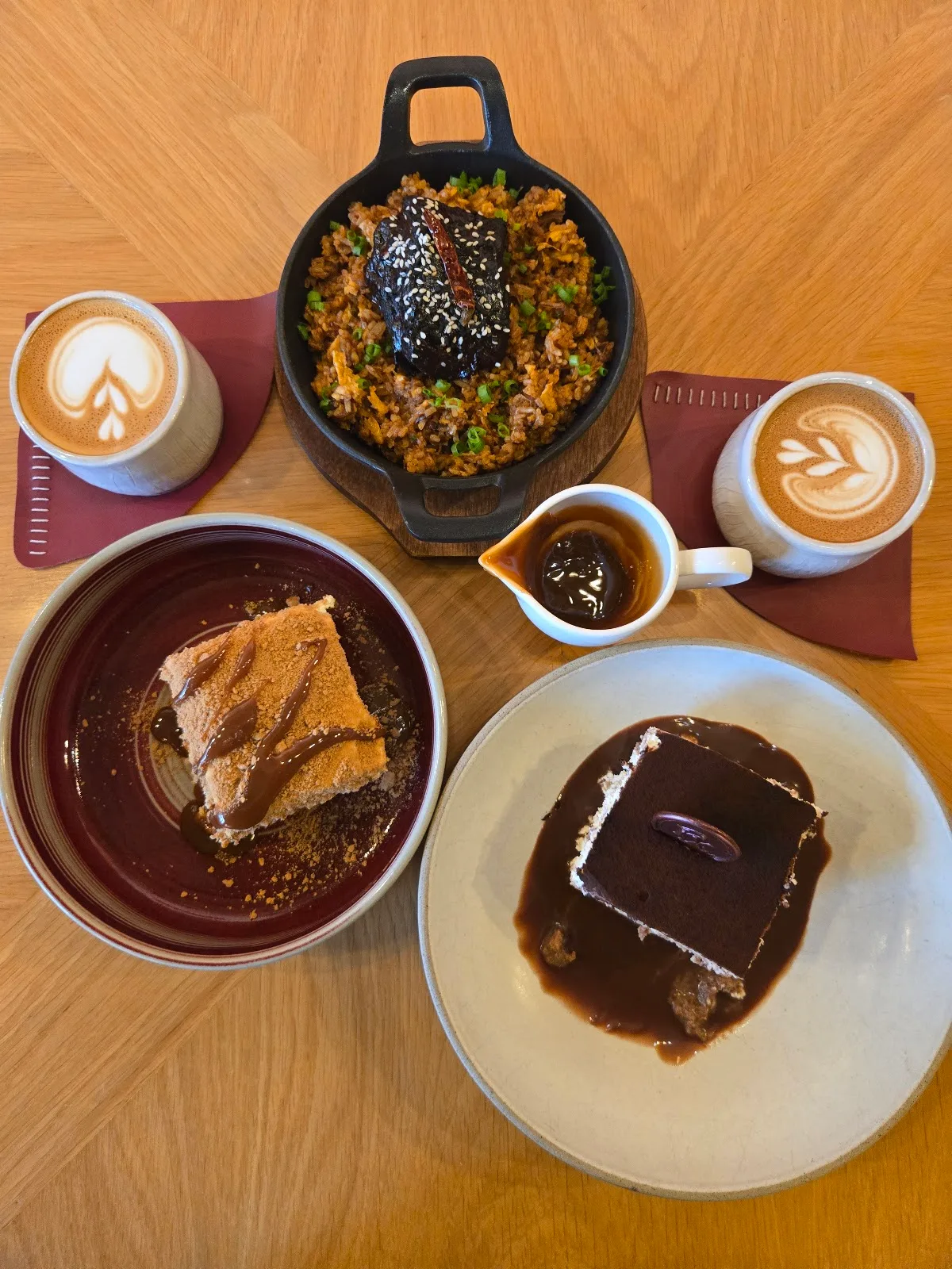 A spread of desserts and lattes on a wooden table