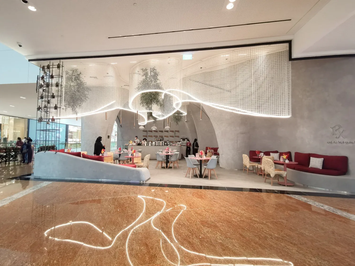 Wide view of the Rx Coffee Apothecary hall with neon canopy and red seating
