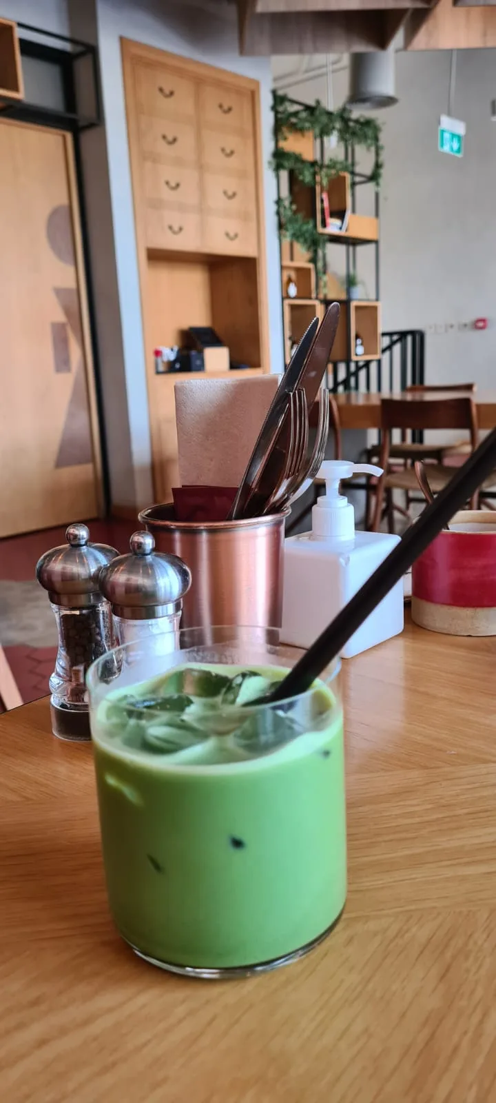 Iced matcha latte in a glass on a wooden café table