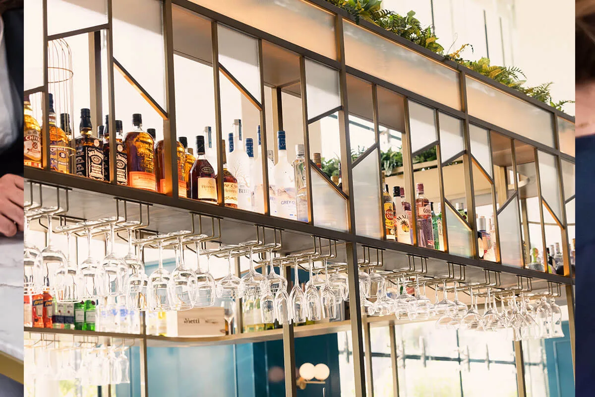 Backlit bar with hanging glassware and a wall of bottles
