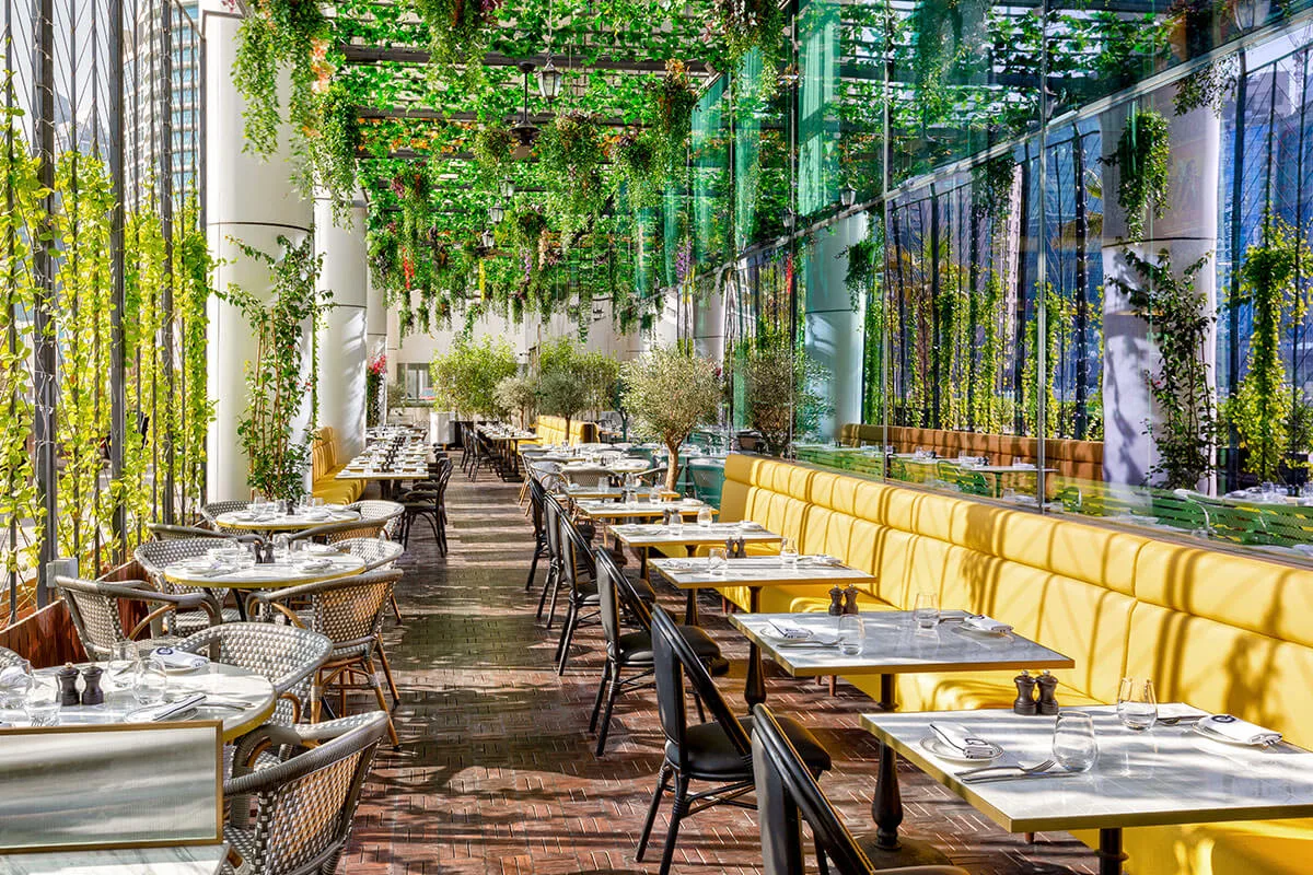 Couqley's leafy green-trellis terrace lined with banquette seating in Business Bay, Dubai