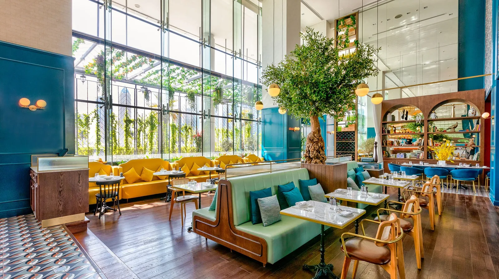 Bright Couqley interior with a teal sofa, arches, plants and patterned tiles