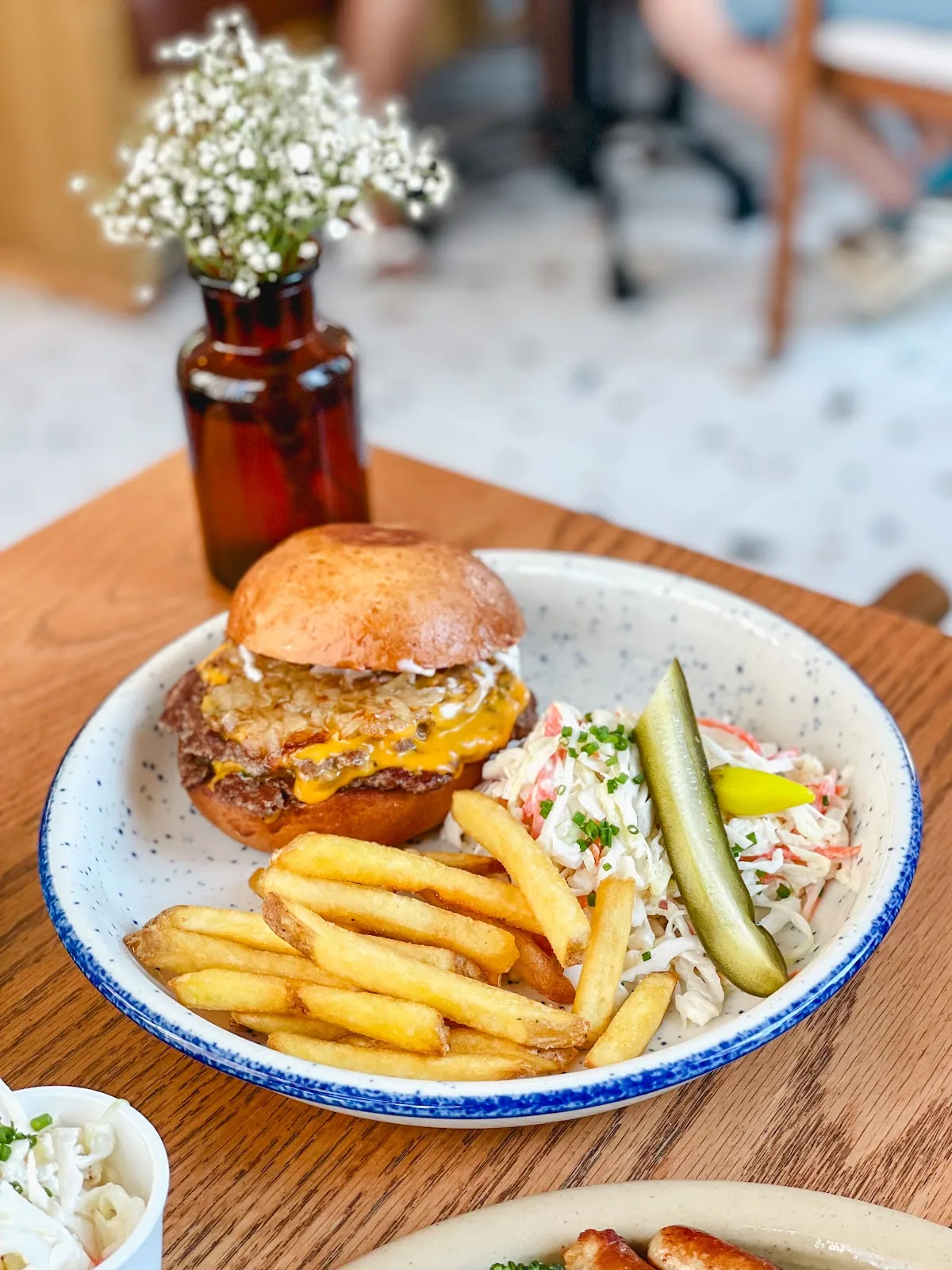 Cheeseburger with fries, slaw and a pickle in a speckled bowl
