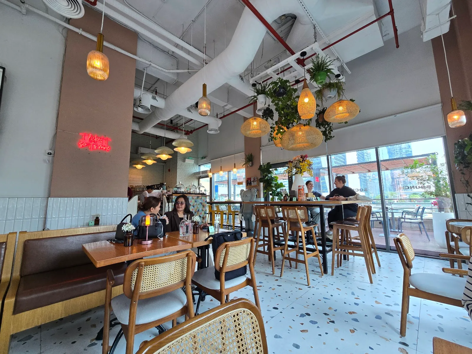 Cafe interior with neon sign, terrazzo floor and guests at wooden tables