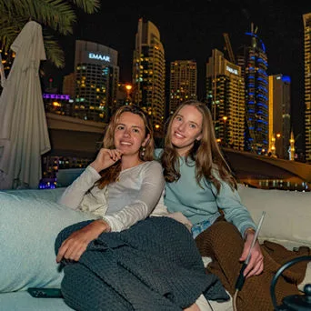Guests on a couch with the Dubai Marina skyline lit up behind them