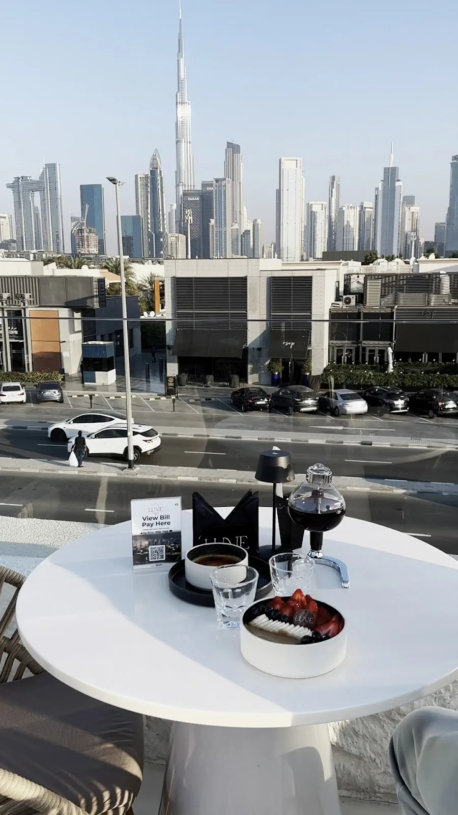 Daytime rooftop table with coffee and the Dubai skyline.