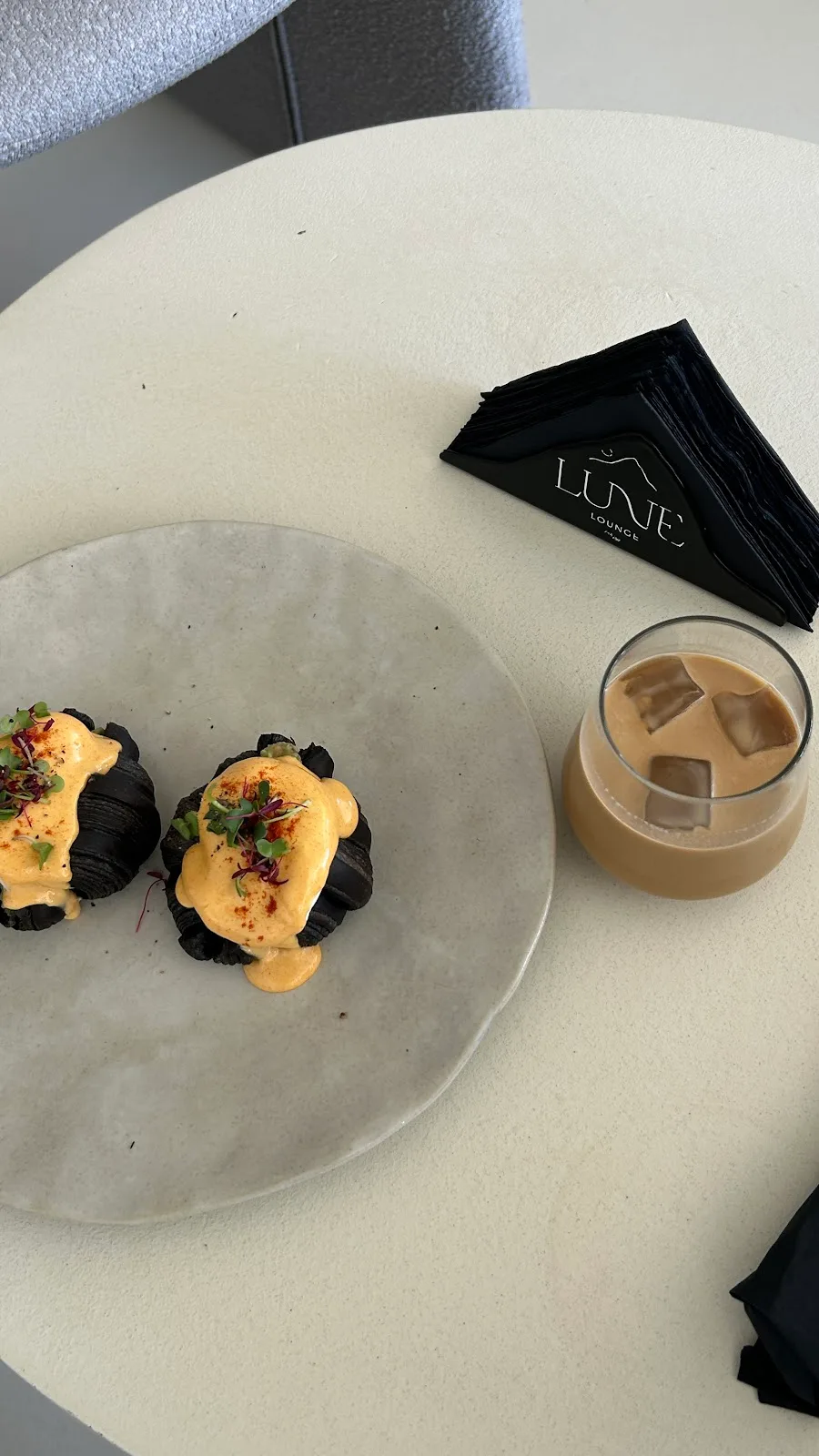 Charcoal eggs benedict and an iced latte with Lune napkins.