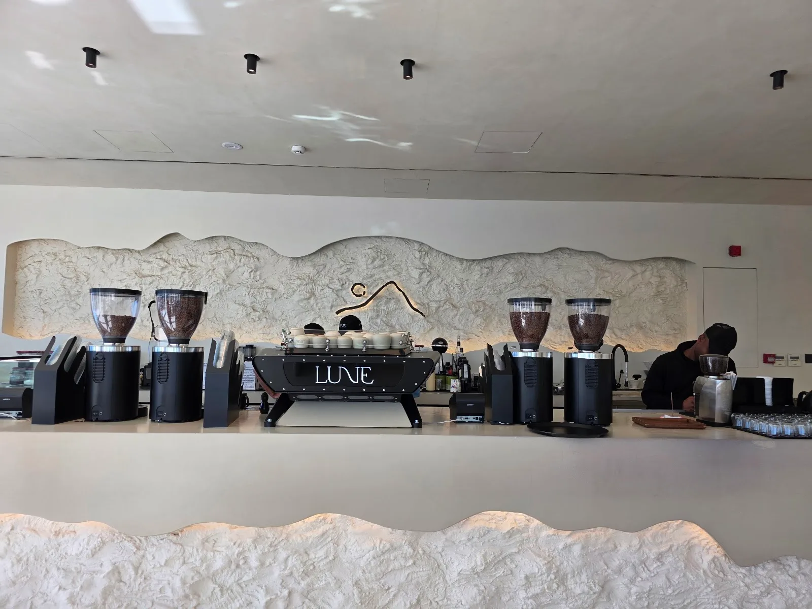 The Lune espresso bar and brand mark on the plaster wall.