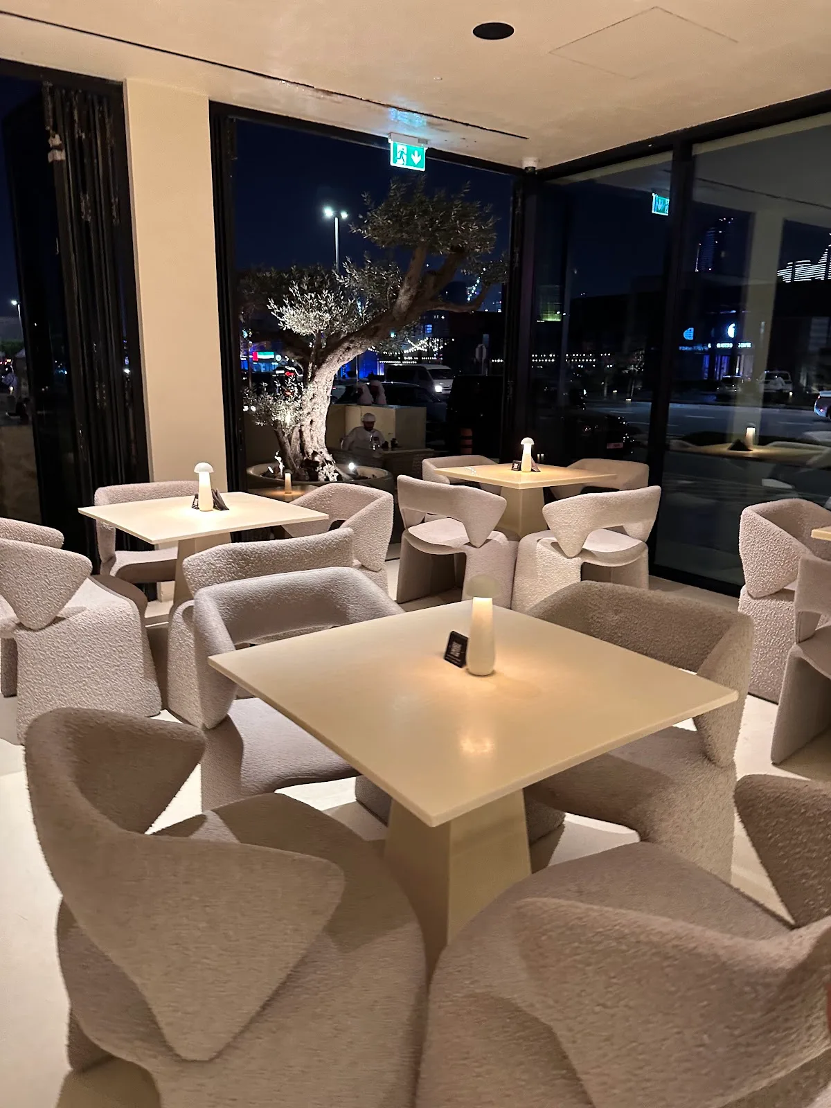 Cream bouclé armchairs in the Lune lounge at night.