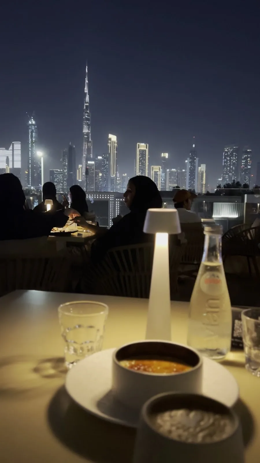 Guests on the rooftop at night with the lit skyline.