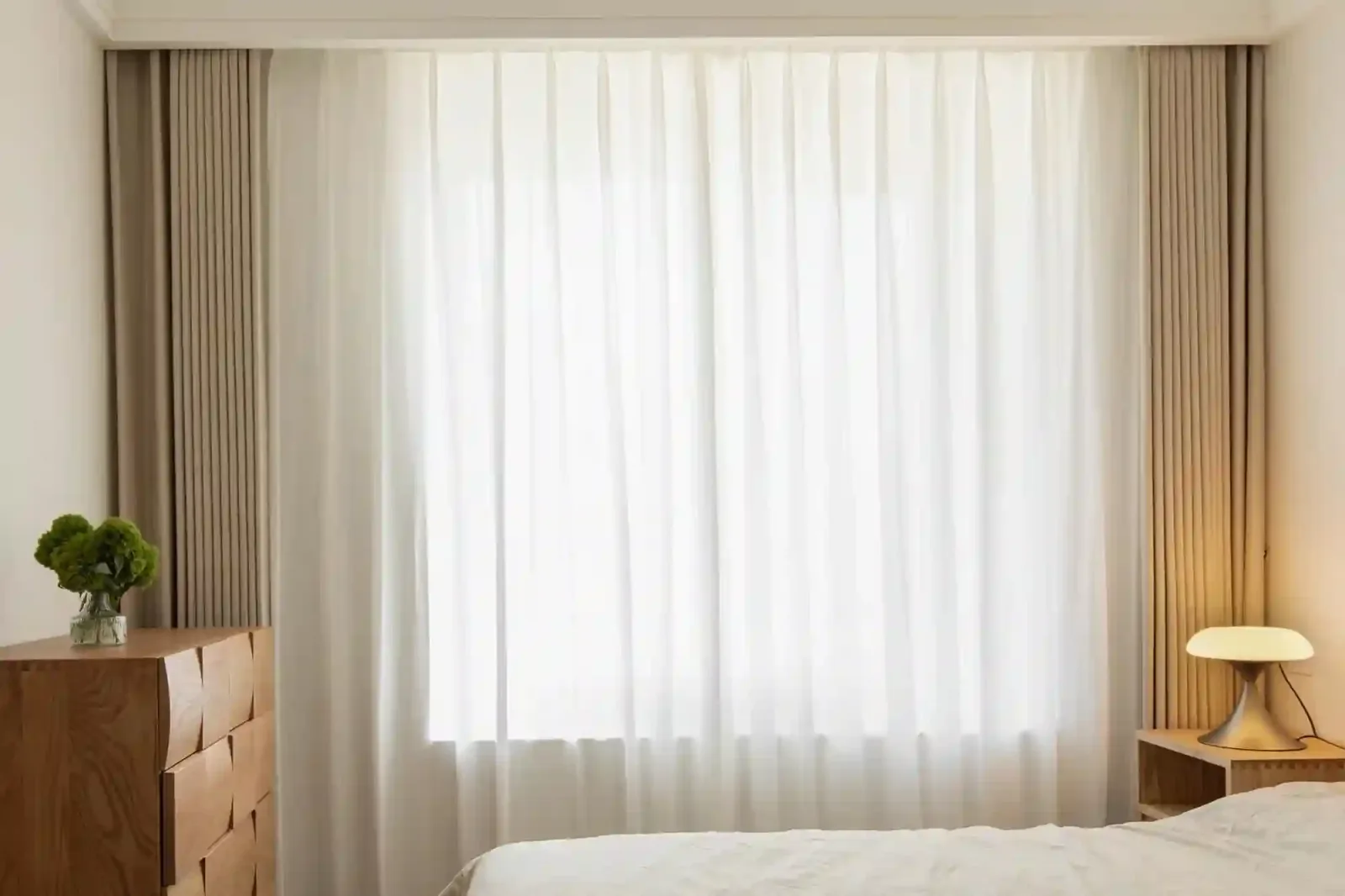 Layered sheer and dim-out curtains framing a bedroom window