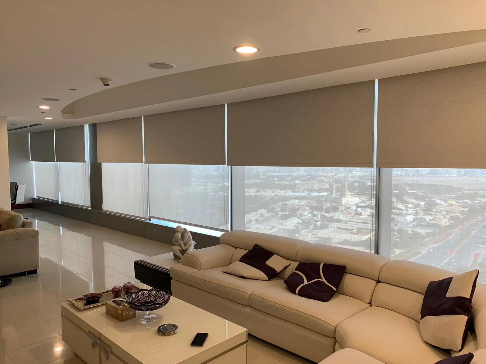 Roller blinds across a wall of windows with a Dubai skyline view