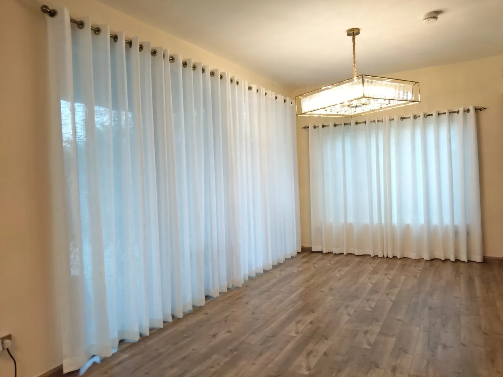 Floor-length sheer eyelet curtains in a bright open-plan room