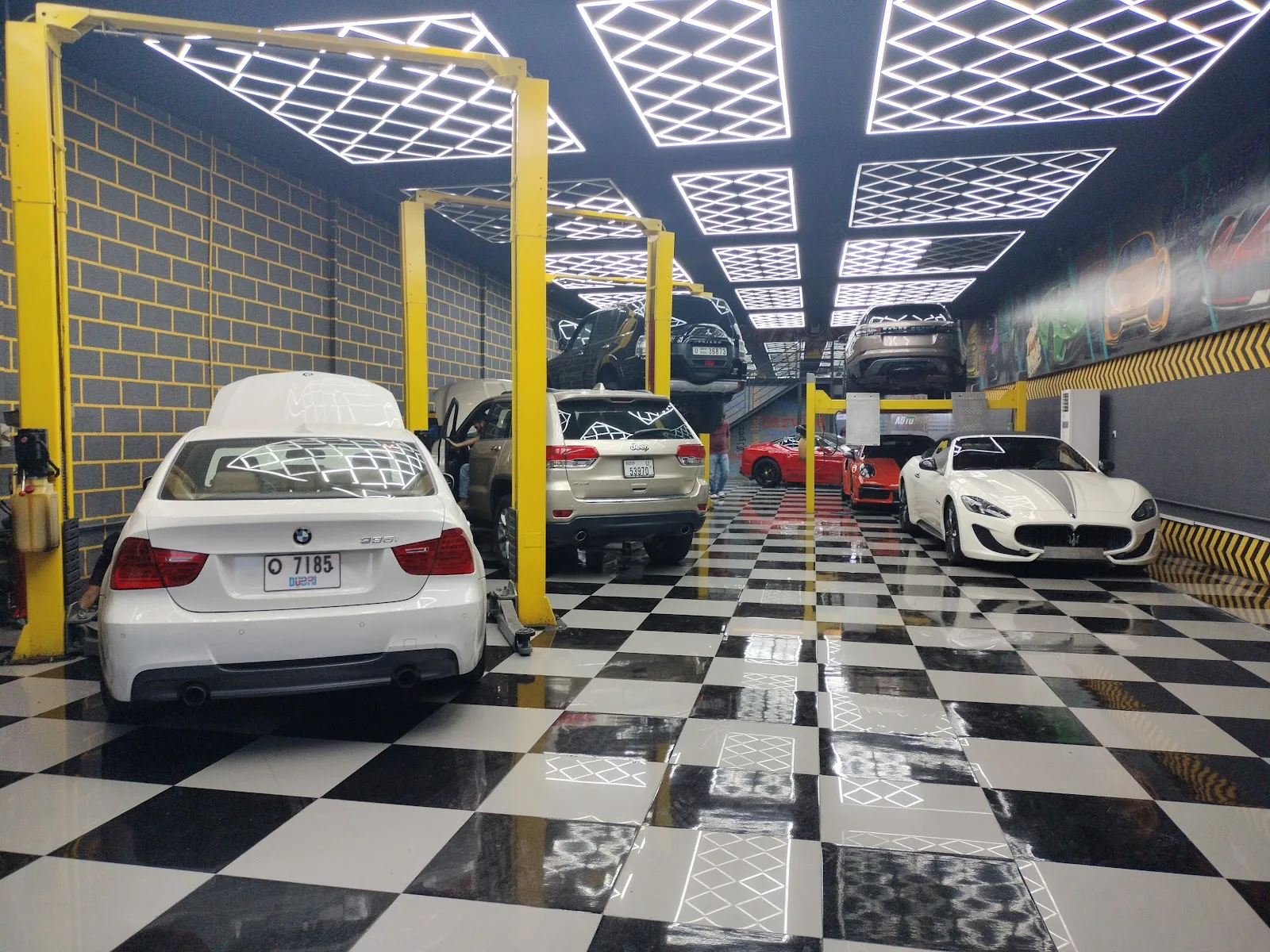 Interior of Auto Whiz Garage with cars on lifts and a glossy checkered floor