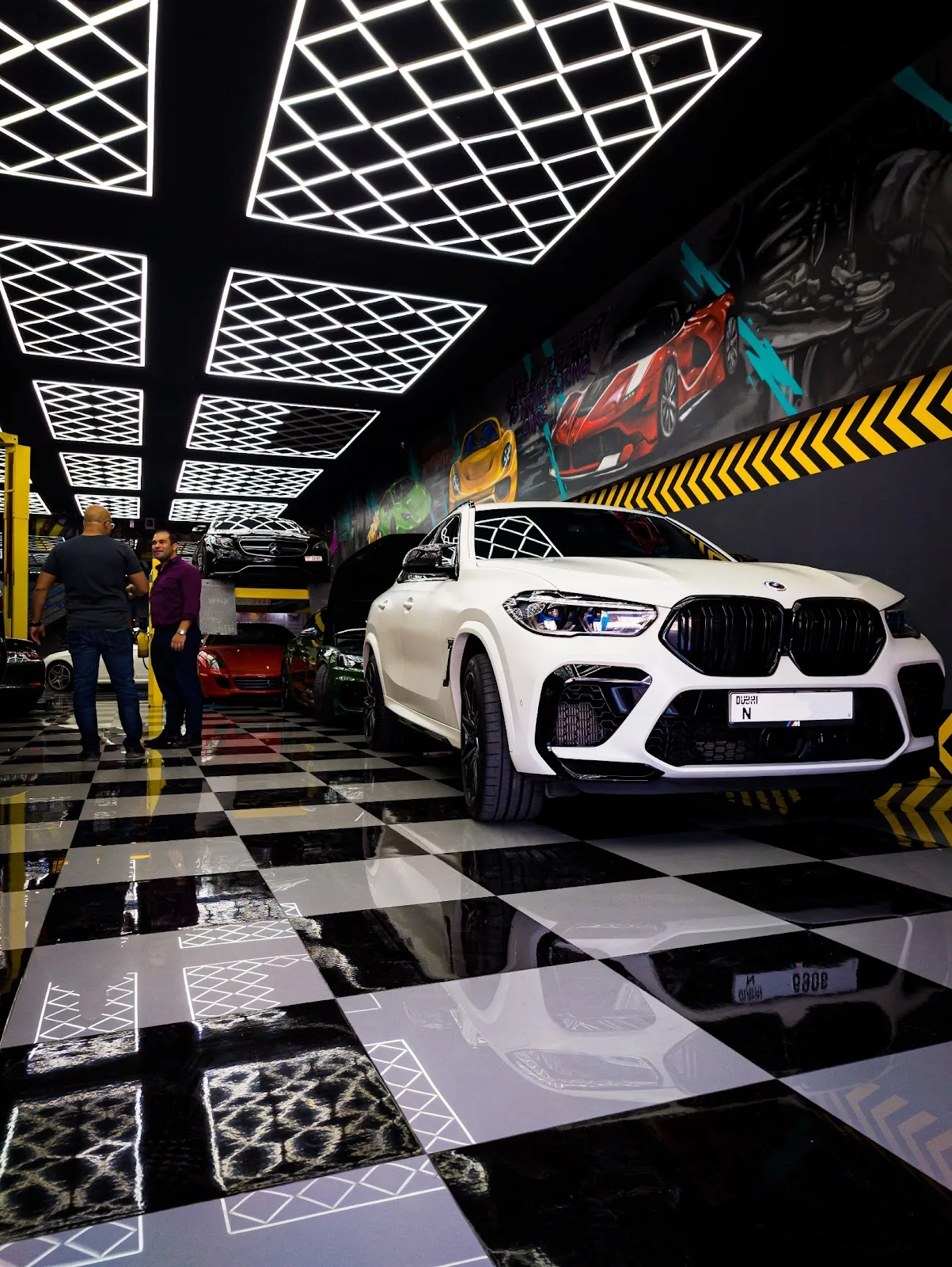 White BMW under diamond LED ceiling lights on a checkered floor