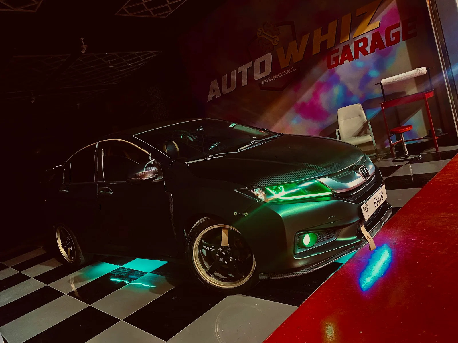 Car lit with neon under the Auto Whiz Garage signage