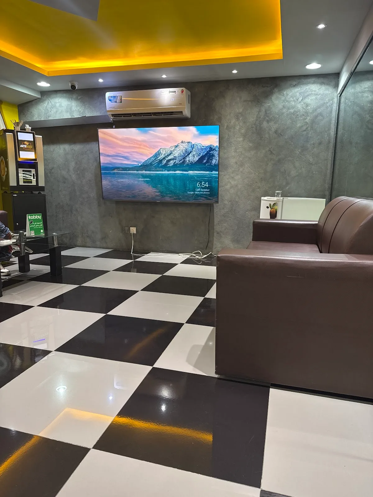 The Auto Whiz Garage customer waiting lounge with a sofa and TV