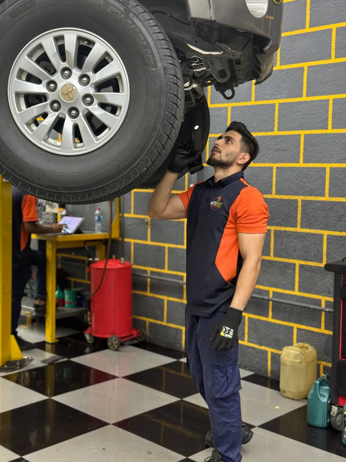 Technician inspecting a wheel and underbody on a lifted SUV
