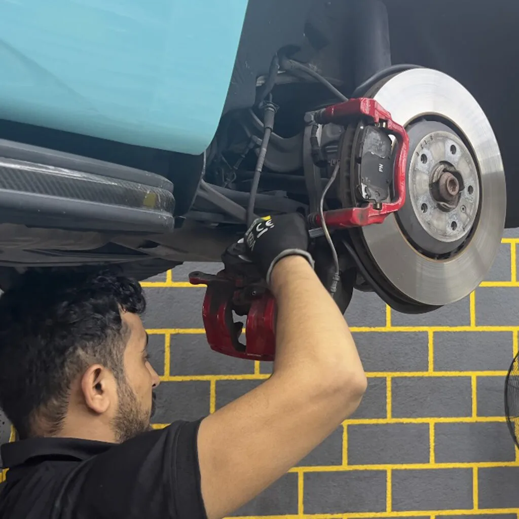 Technician working on a brake caliper and disc