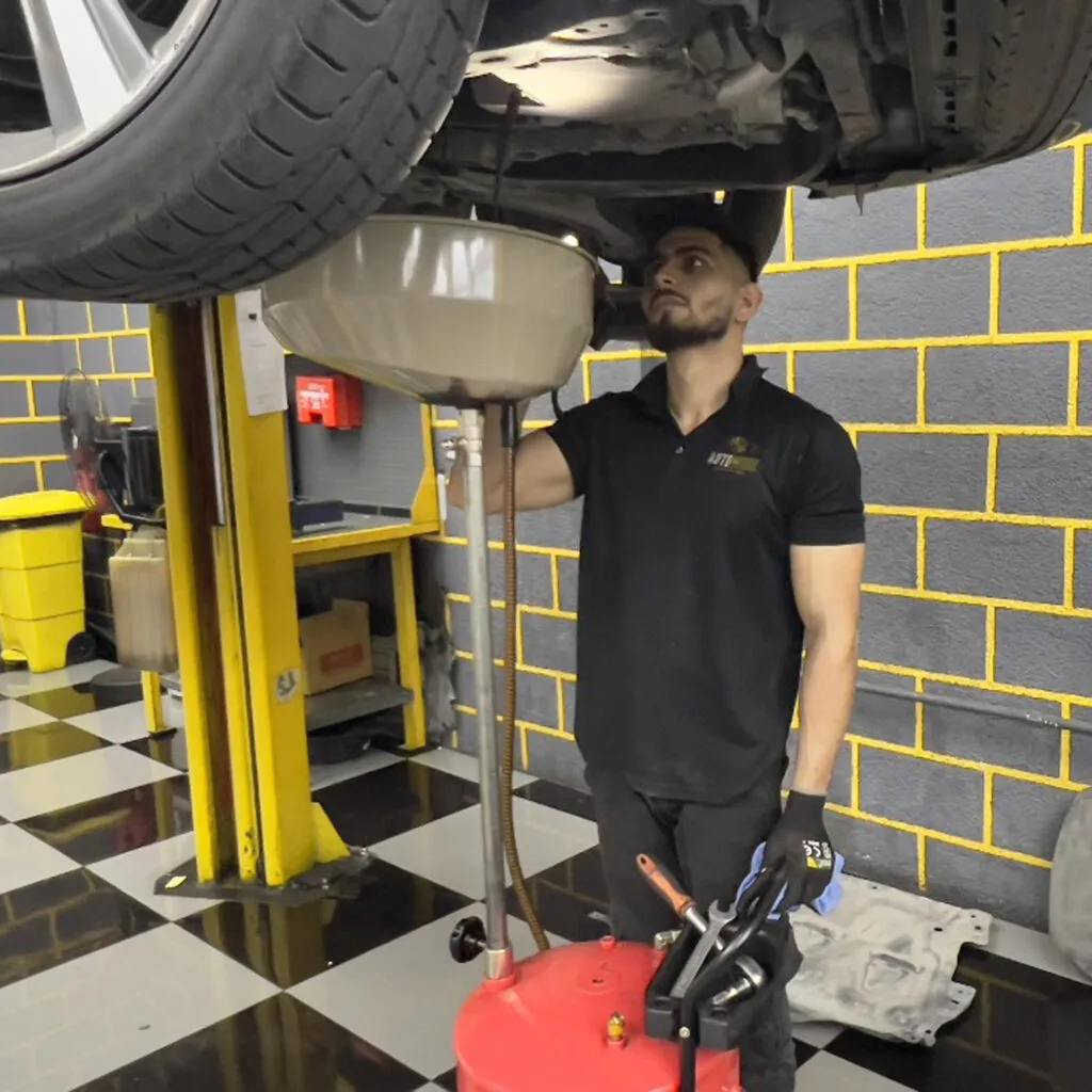 Technician draining oil from a vehicle on a lift