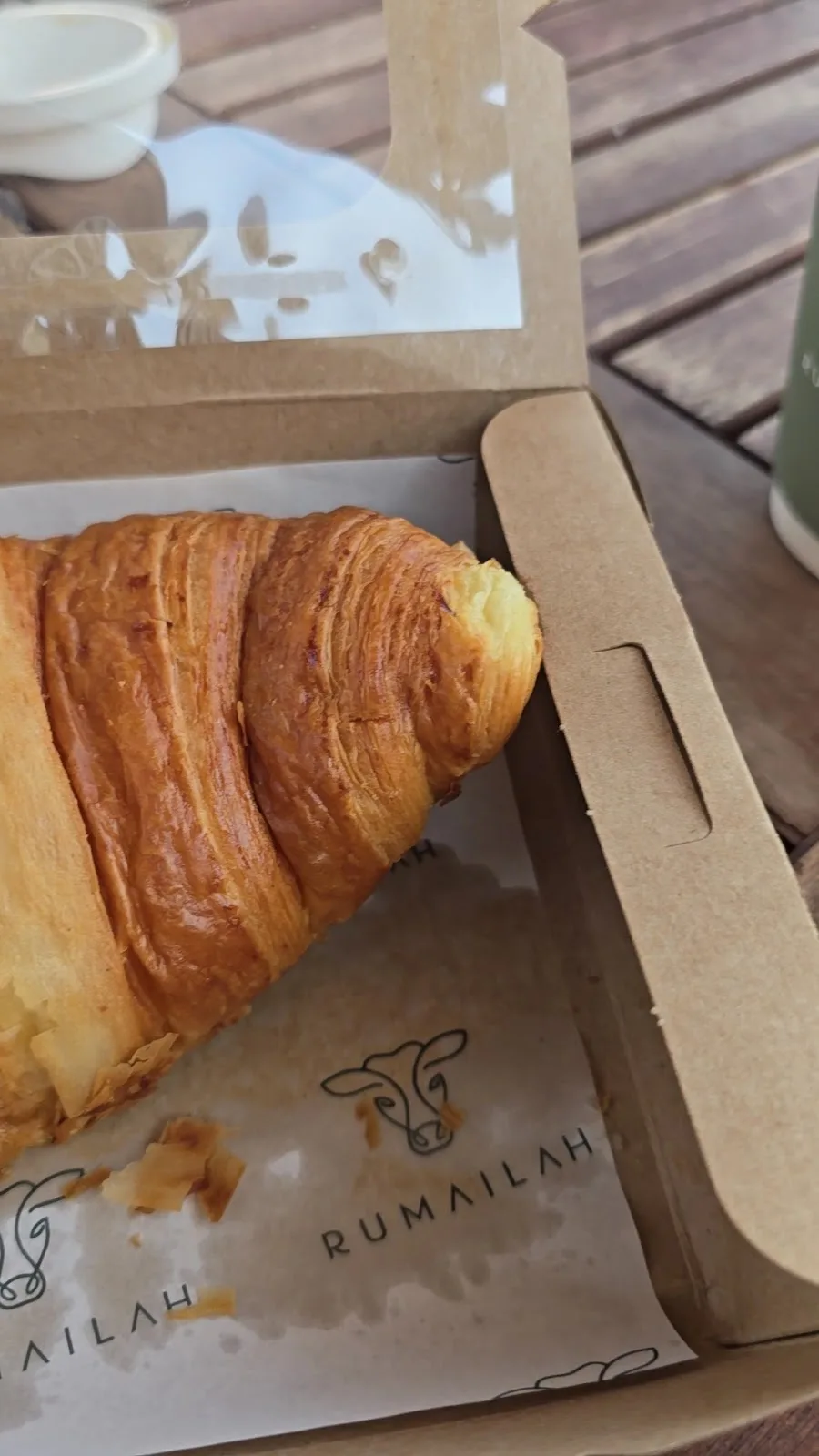 Close-up of a golden croissant on Rumailah branded paper