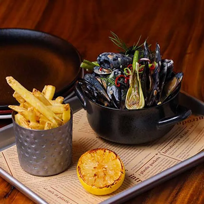 Pot of steamed mussels with chilli and herbs, served with hand-cut fries and charred lemon