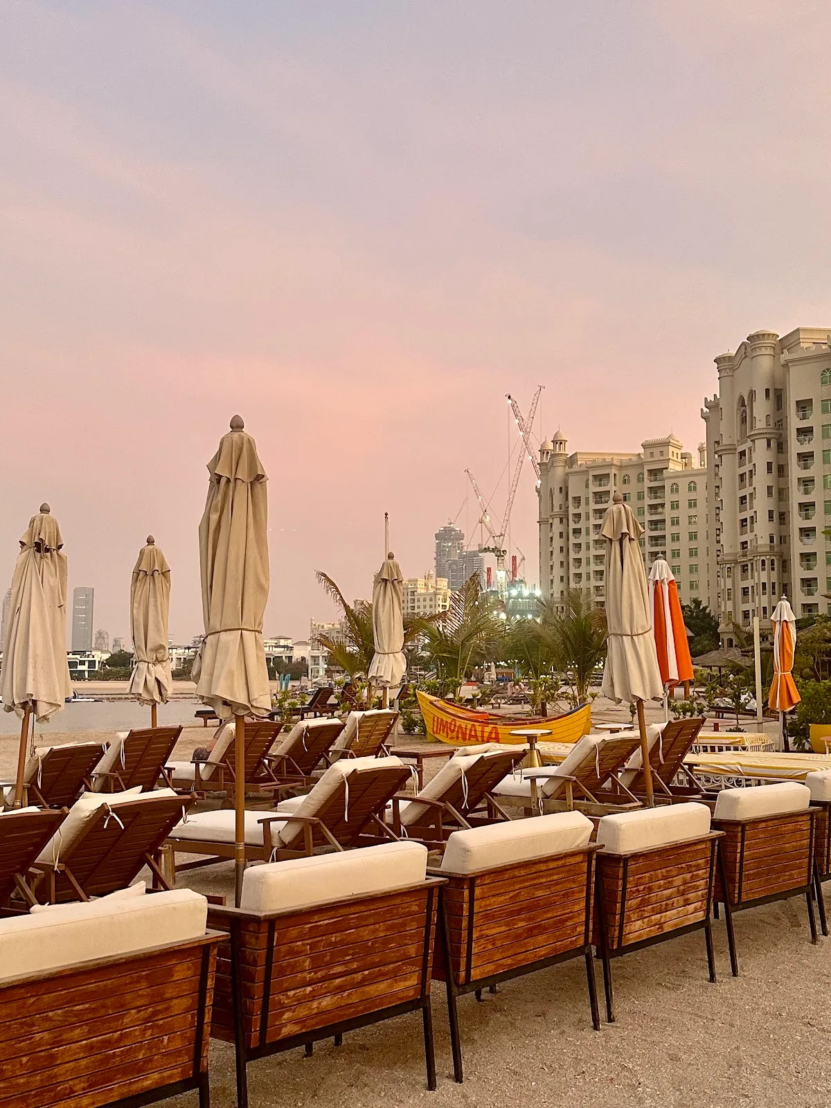 Beach loungers under a pink sunset sky