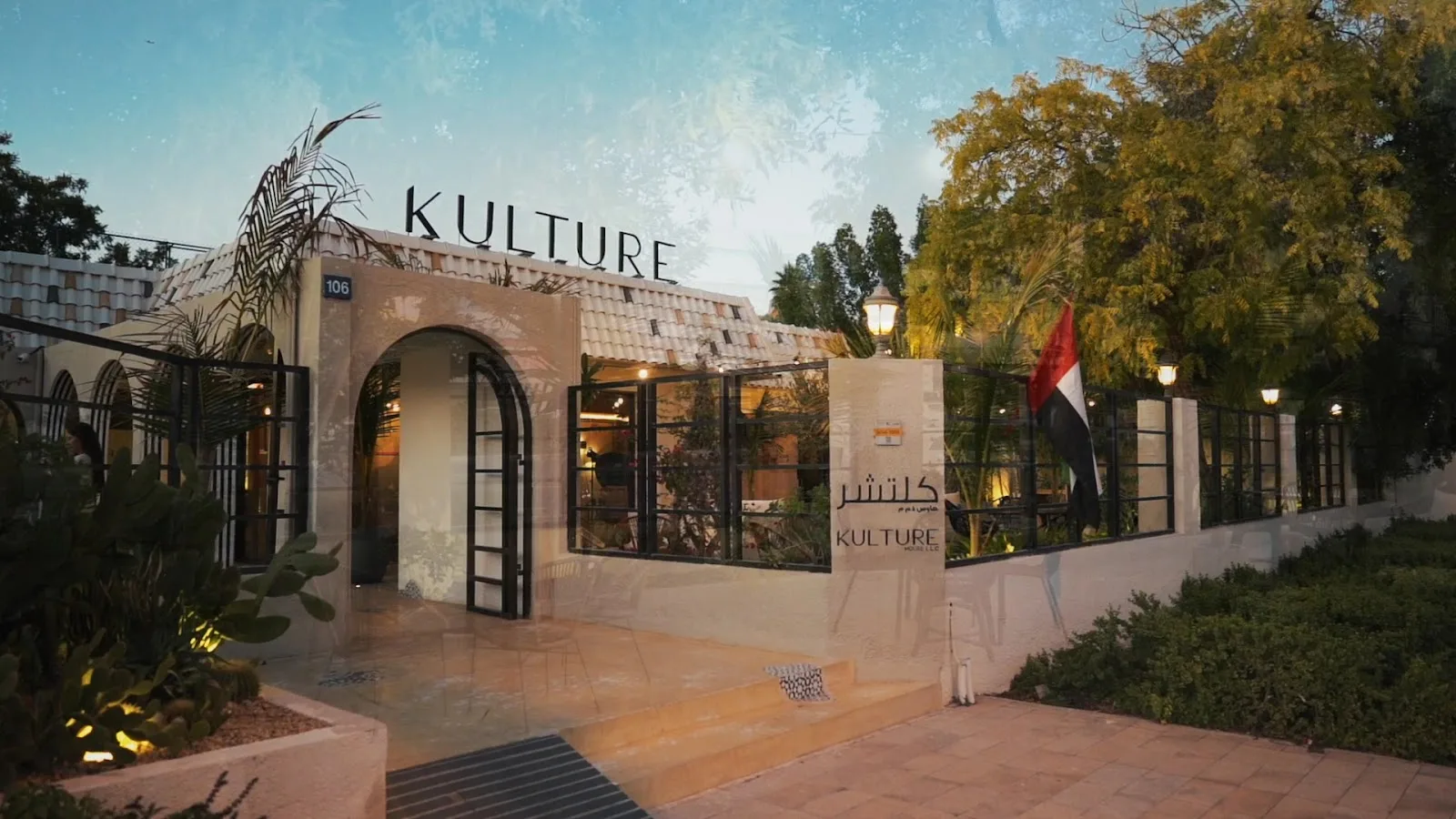 The Kulture House villa at dusk, with its arched entrance and KULTURE signage lit against the evening sky.