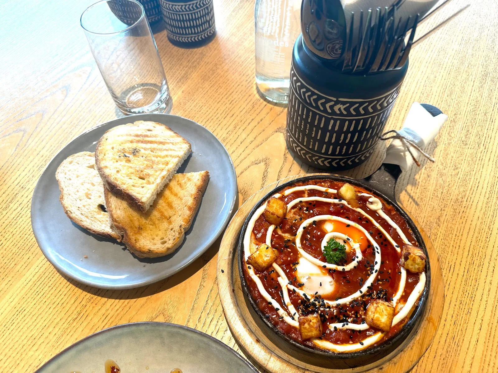 Shakshuka in a cast-iron dish swirled with yoghurt, served with grilled sourdough toast.