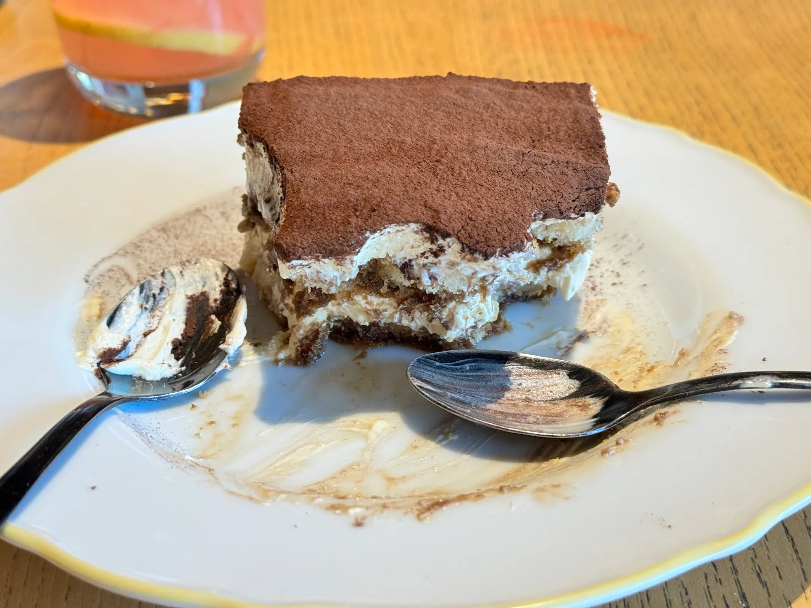 A slice of dusted tiramisu on a scalloped plate.