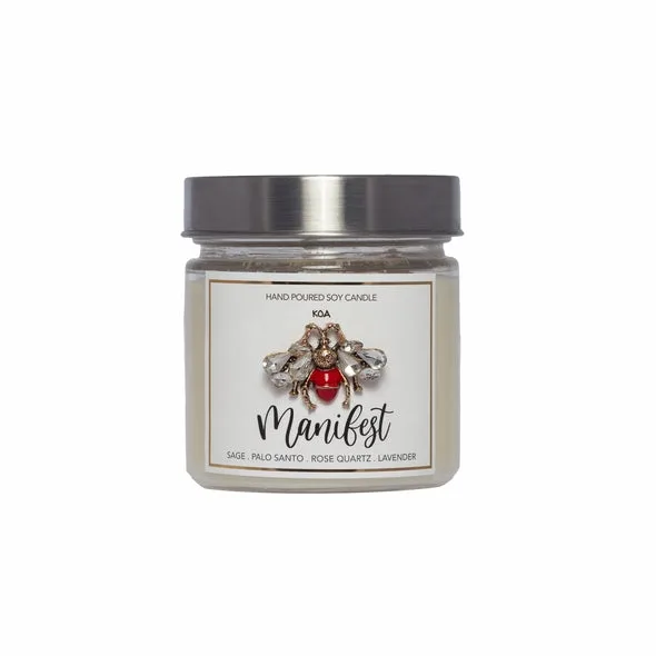A hand-poured soy candle labelled ‘Manifest’ with a jewelled bee detail.
