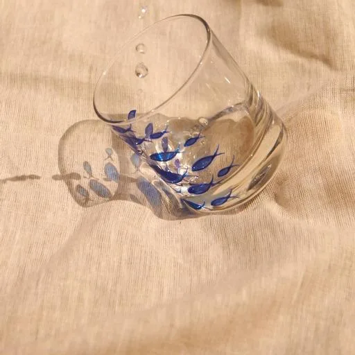 A tumbler hand-painted with a shoal of blue fish on linen.
