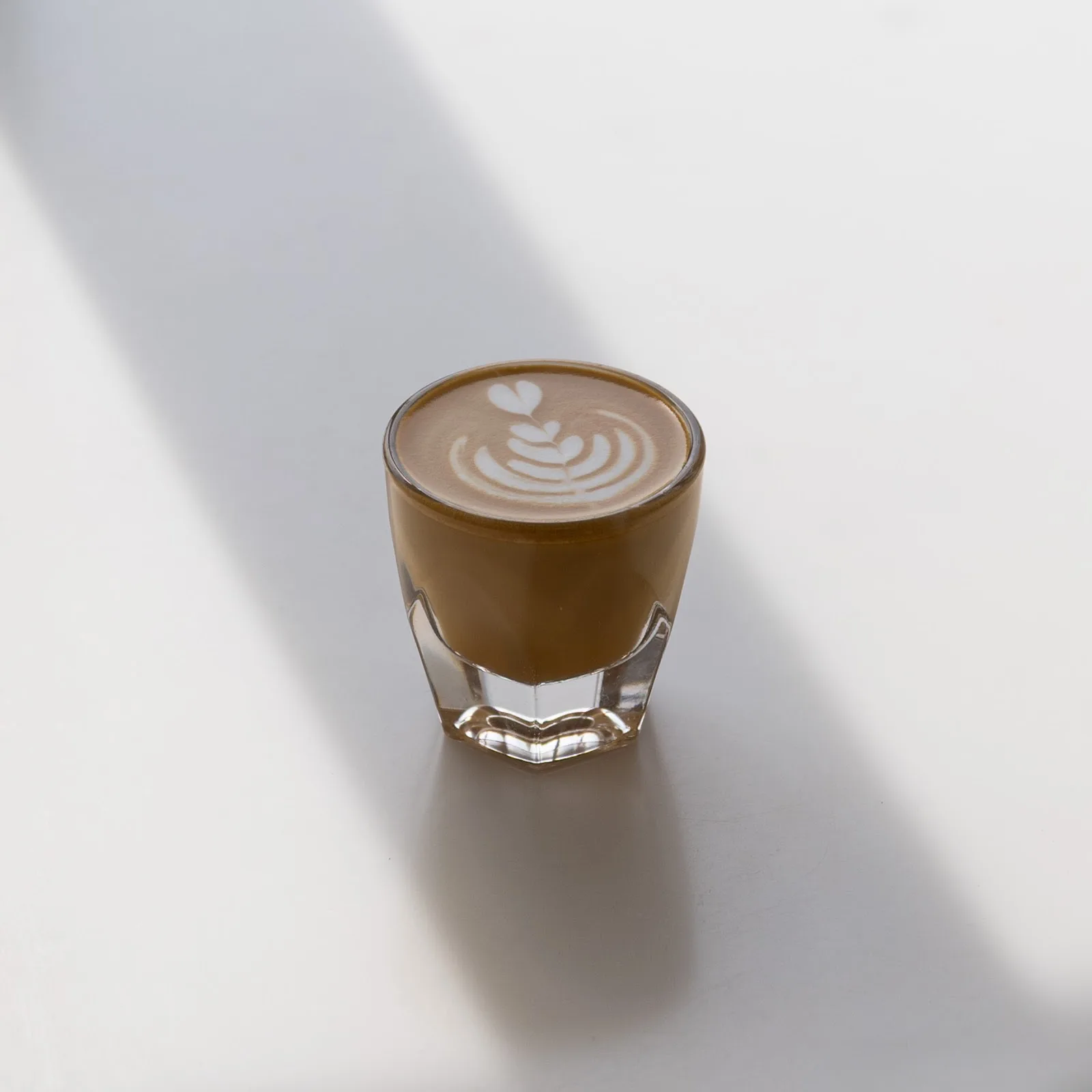 Cortado with latte art in a faceted glass