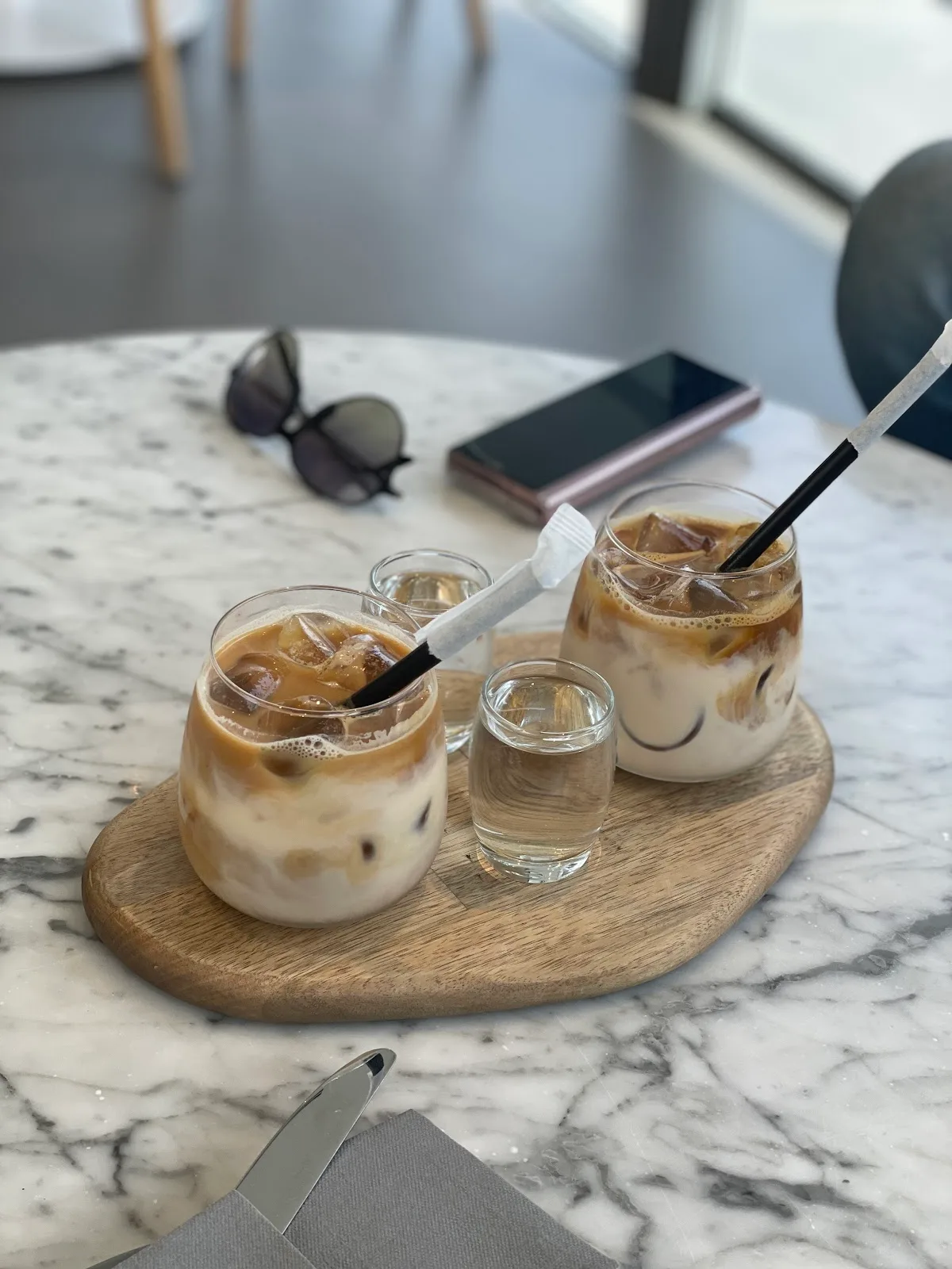Two iced lattes on a wooden board