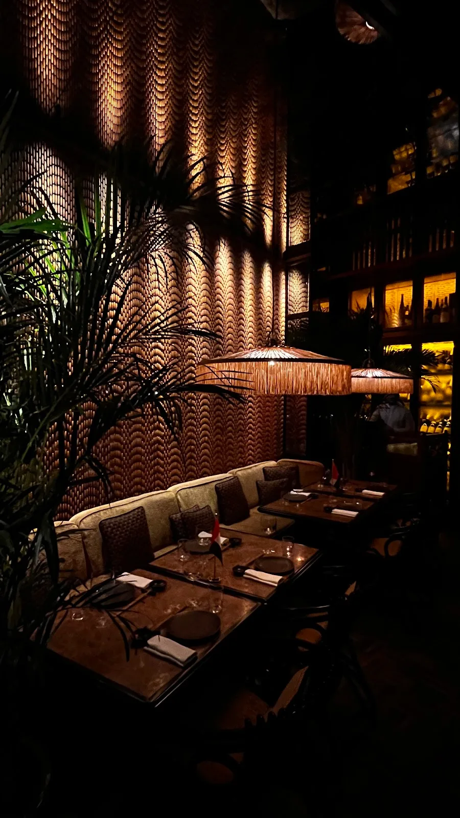 A lamplit banquette against a textured rattan wall