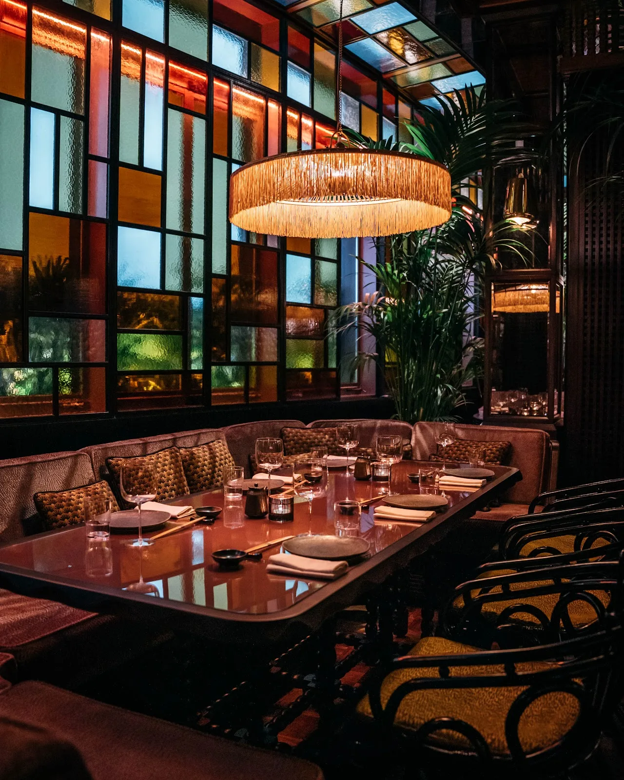 Mimi Kakushi dining room with stained-glass windows and a fringed rattan chandelier