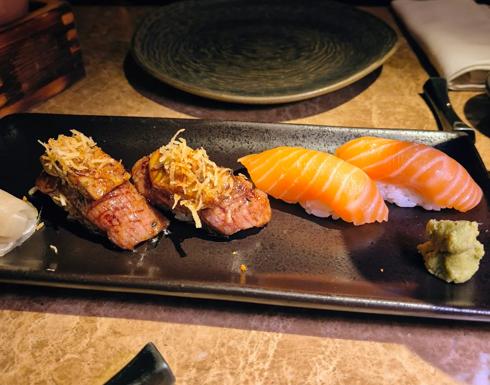 Salmon nigiri and seared selections on a dark plate