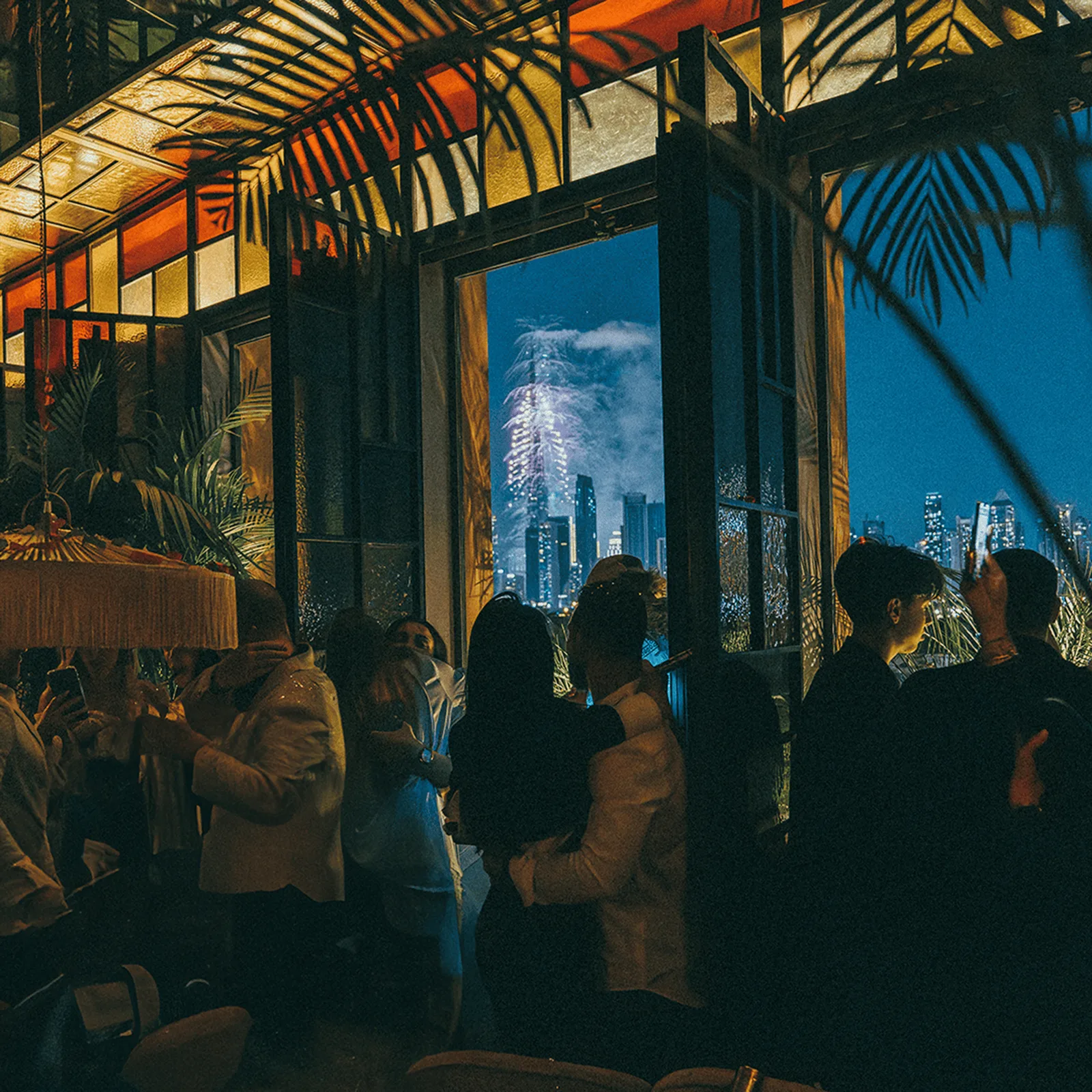 Guests at night with the Dubai skyline and fireworks beyond