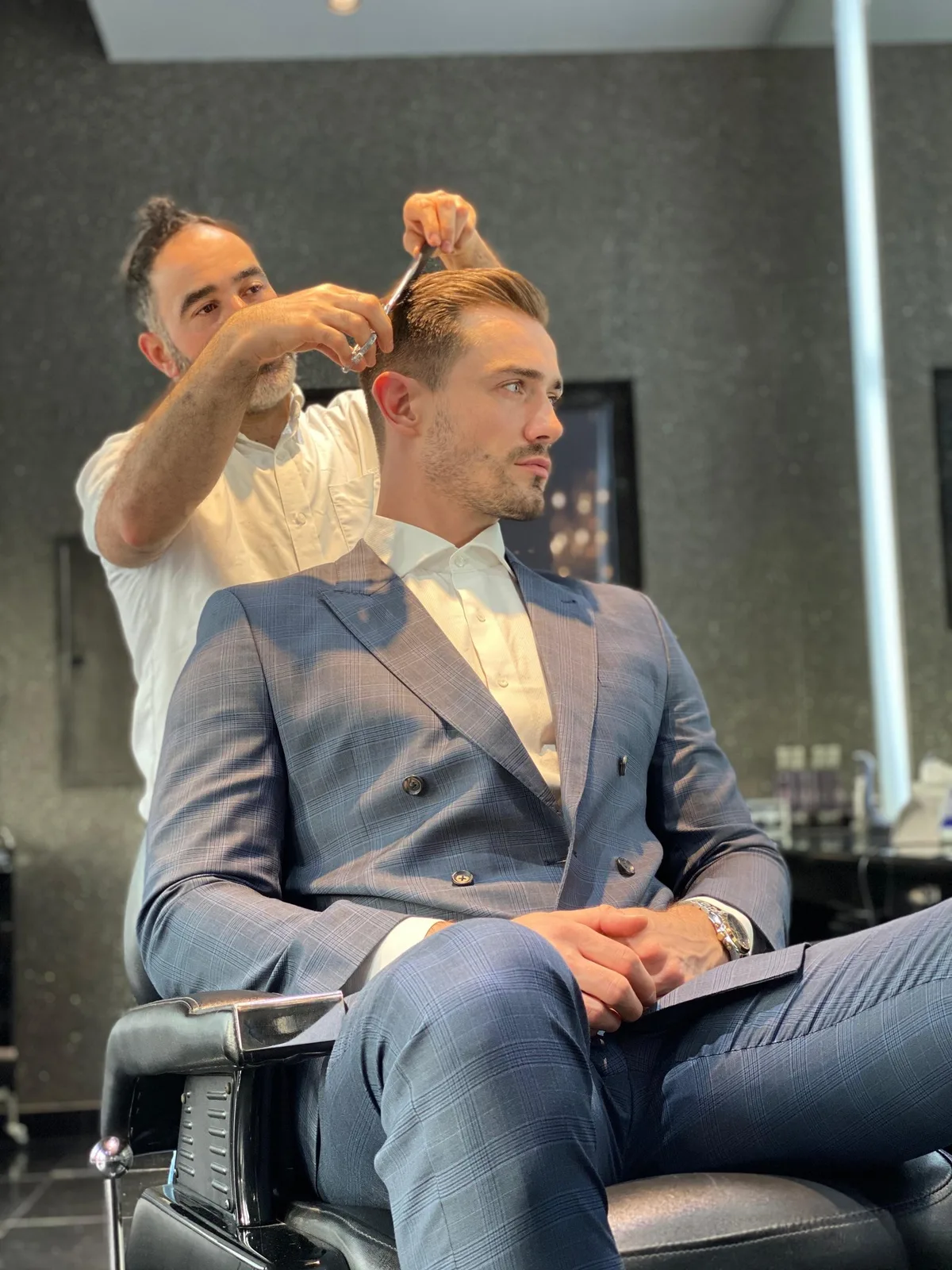 A client in a tailored suit receiving a precision scissor haircut at The Gentlemen's Barber Shop