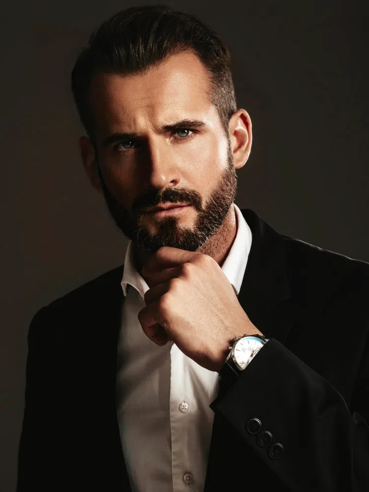 A groomed full beard, styled and shaped
