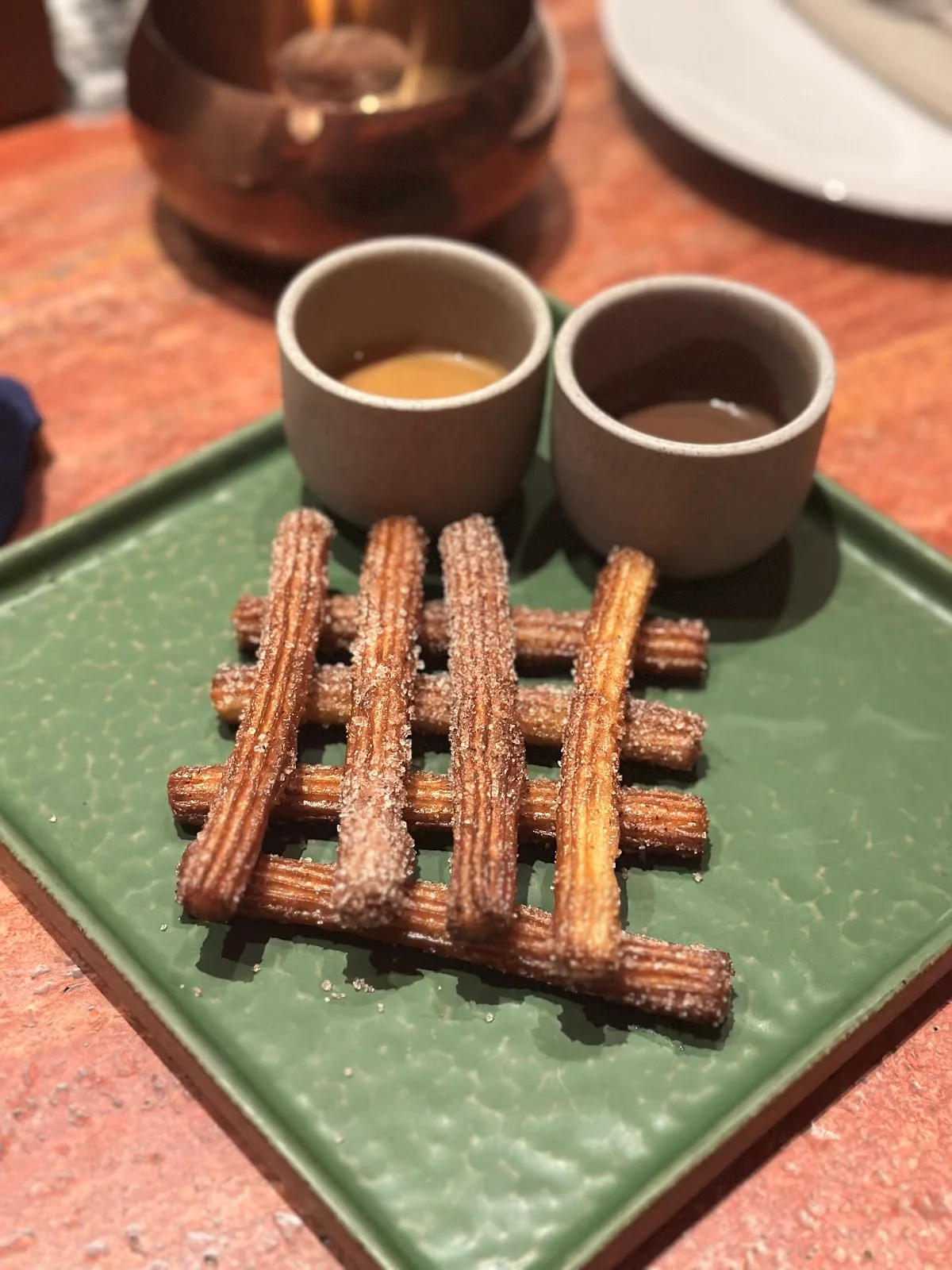 A lattice of cinnamon churros with two dipping sauces