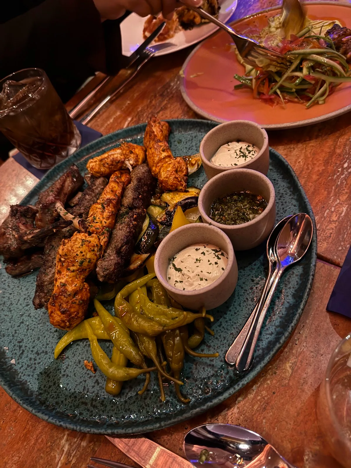 A mixed grill platter of skewers, grilled peppers and dips