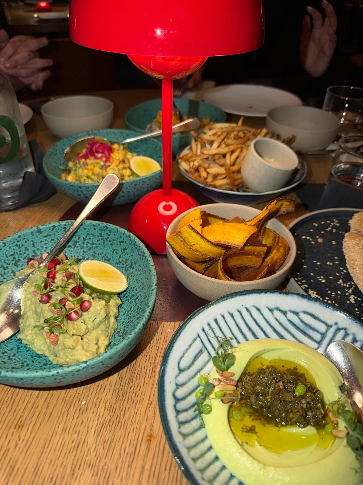 A table of mezze and sharing plates around a red table lamp